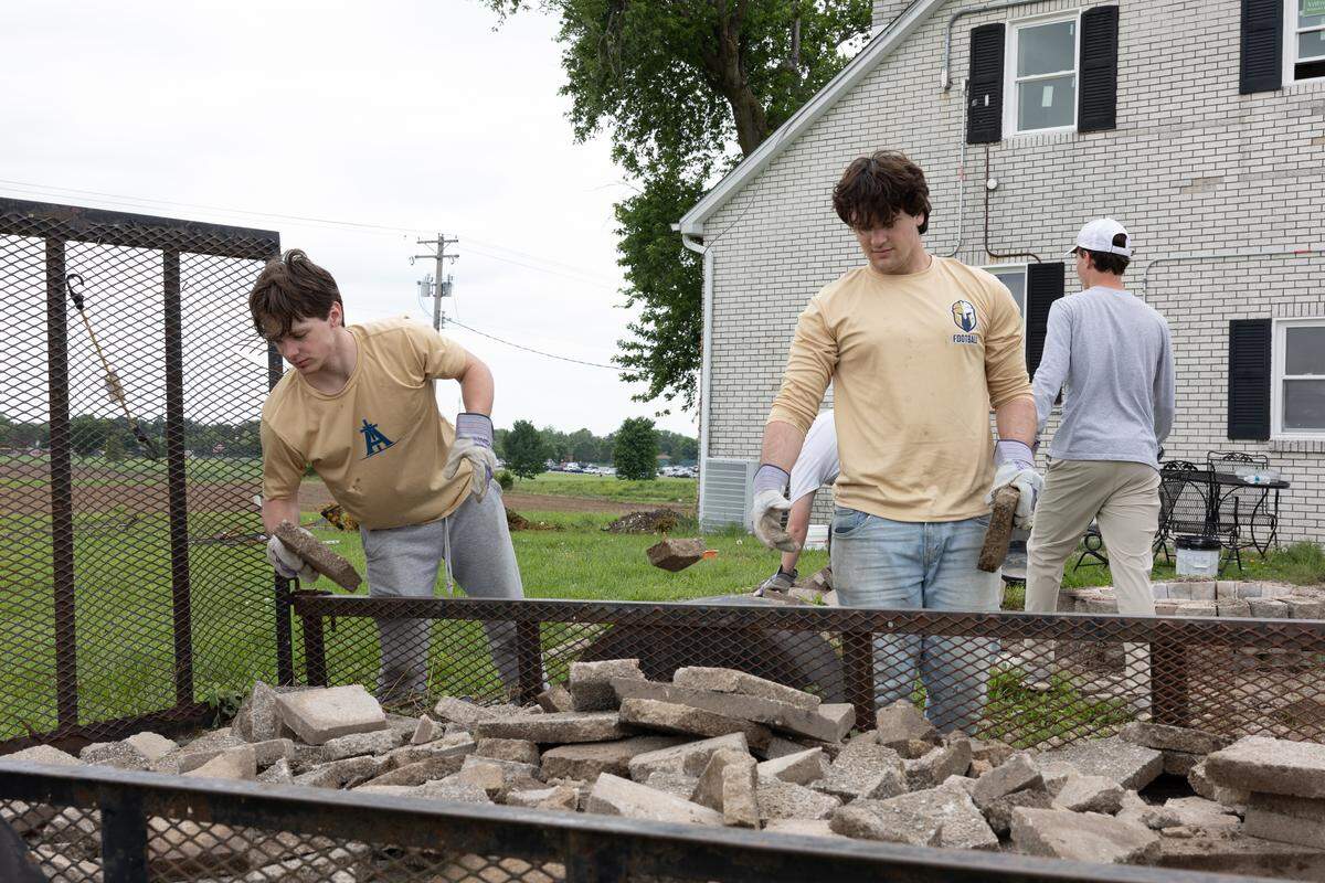 Althoff Catholic High School graduates and other volunteers remove old paving stones to create a garden at a former farm that’s being converted into the new Belleville location of Karla Smith Behavioral Health.